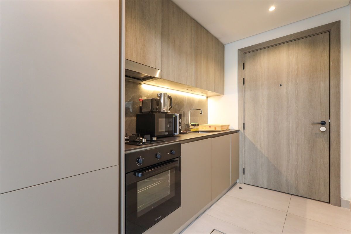 A modern kitchen with built-in appliances, a wooden door, and a tiled floor.