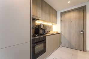 A modern kitchen with built-in appliances, a wooden door, and a tiled floor.
