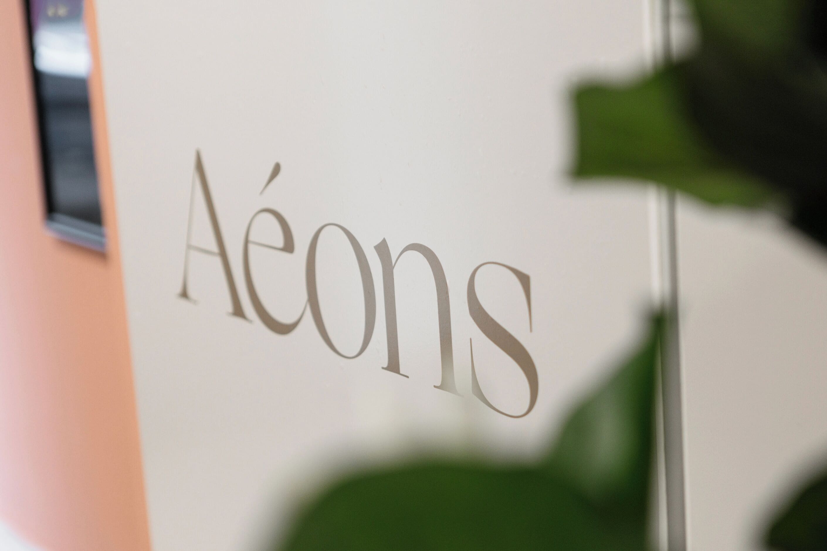 A close-up of a wall with the word "Aéons" in large, elegant script.