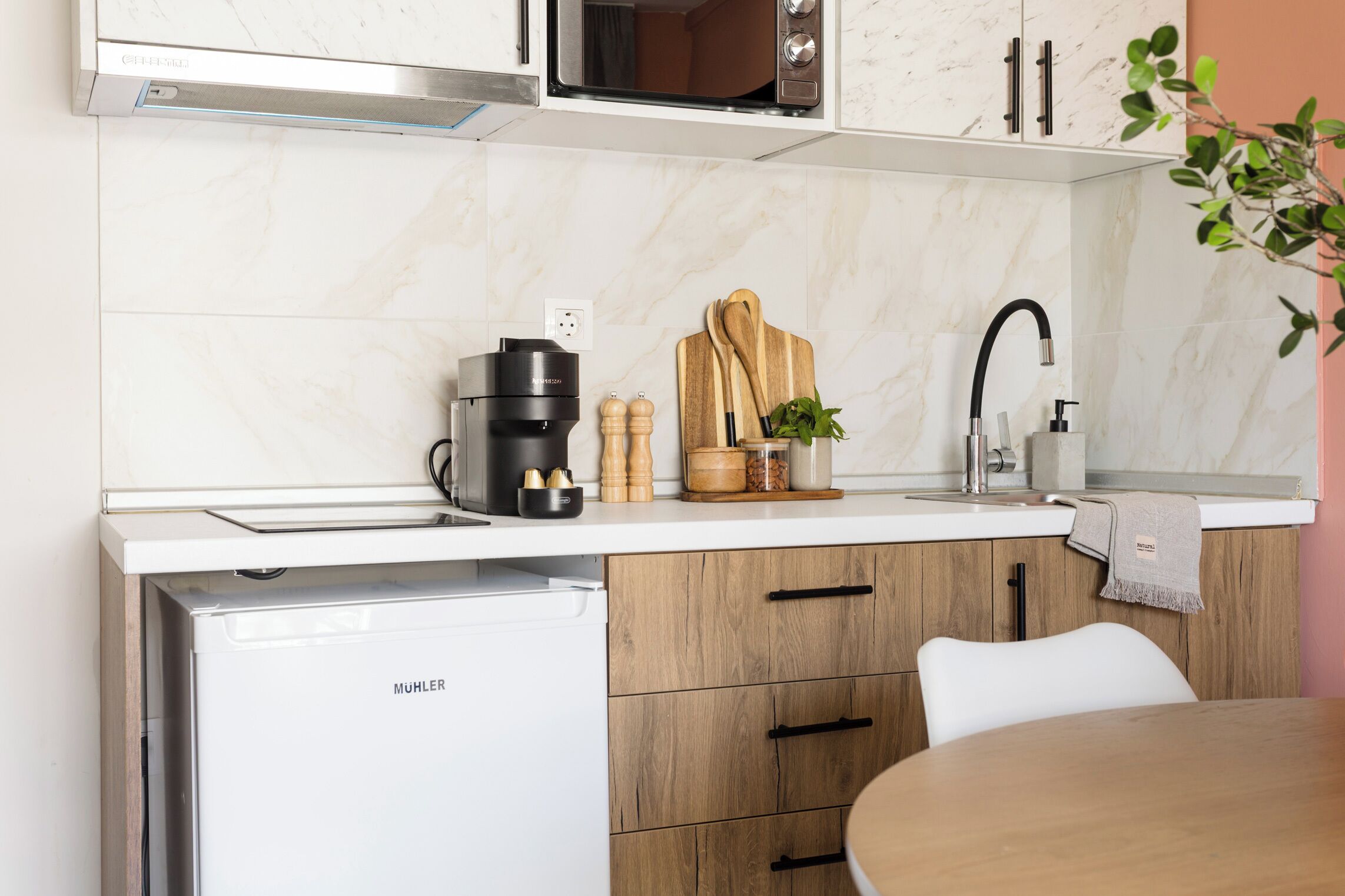 A compact kitchen with a coffee maker, wooden cutting board, and a sink.