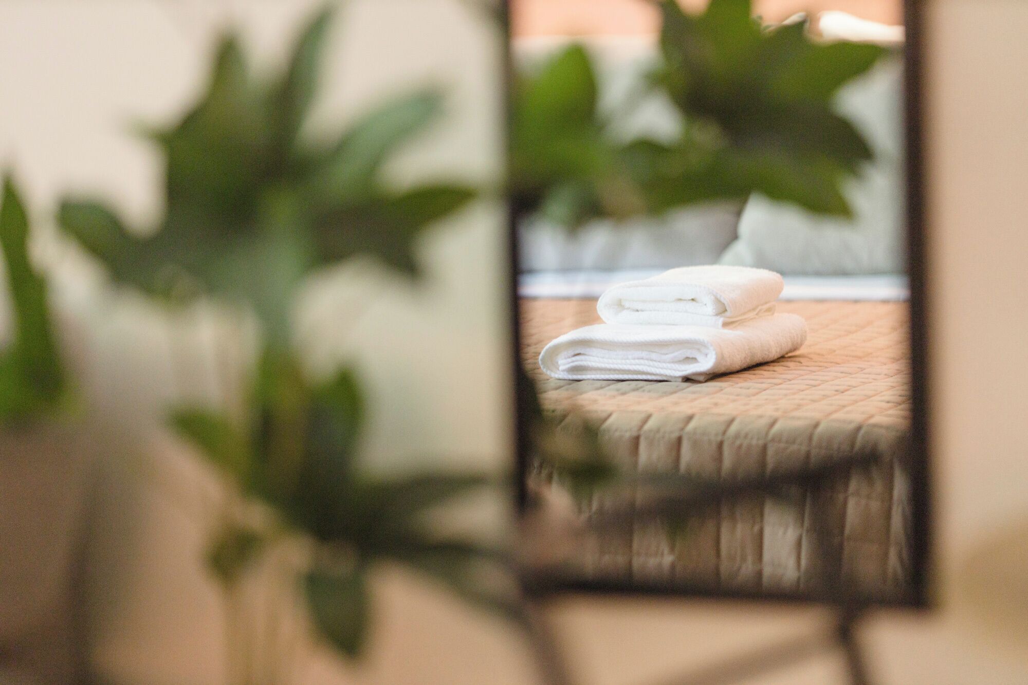 A reflection of a bed with neatly folded white towels.