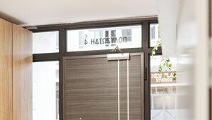 A modern interior with a wooden panel wall, a large window with a view of a car and a building, and a sign above the window reading "HAIR Salon".