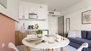 A modern kitchen with marble cabinets, a built-in oven, and a dining area with white chairs and a round table.