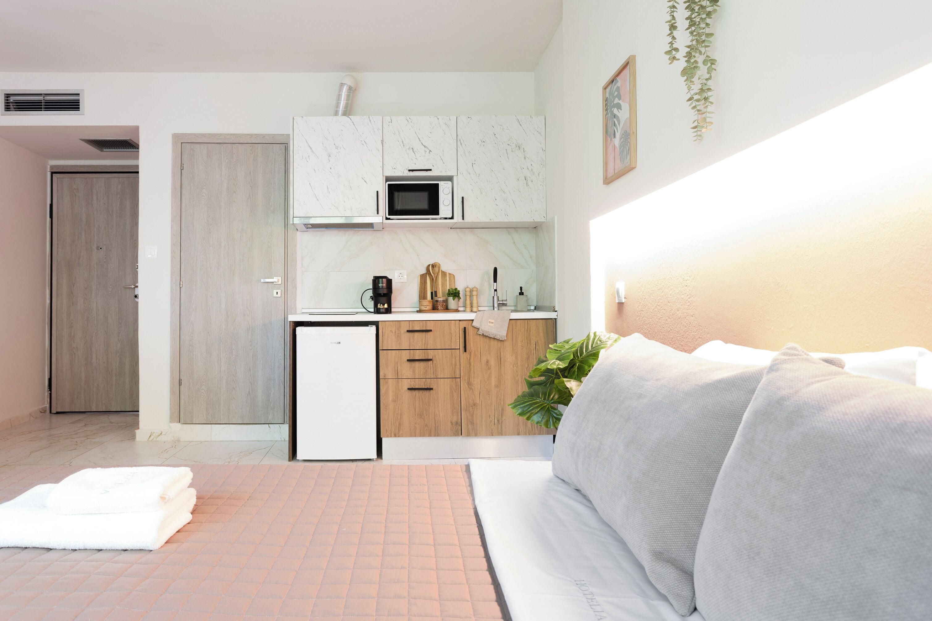 Une chambre d’hôtel compacte comprenant un coin cuisine, un lit et une petite salle de bain.