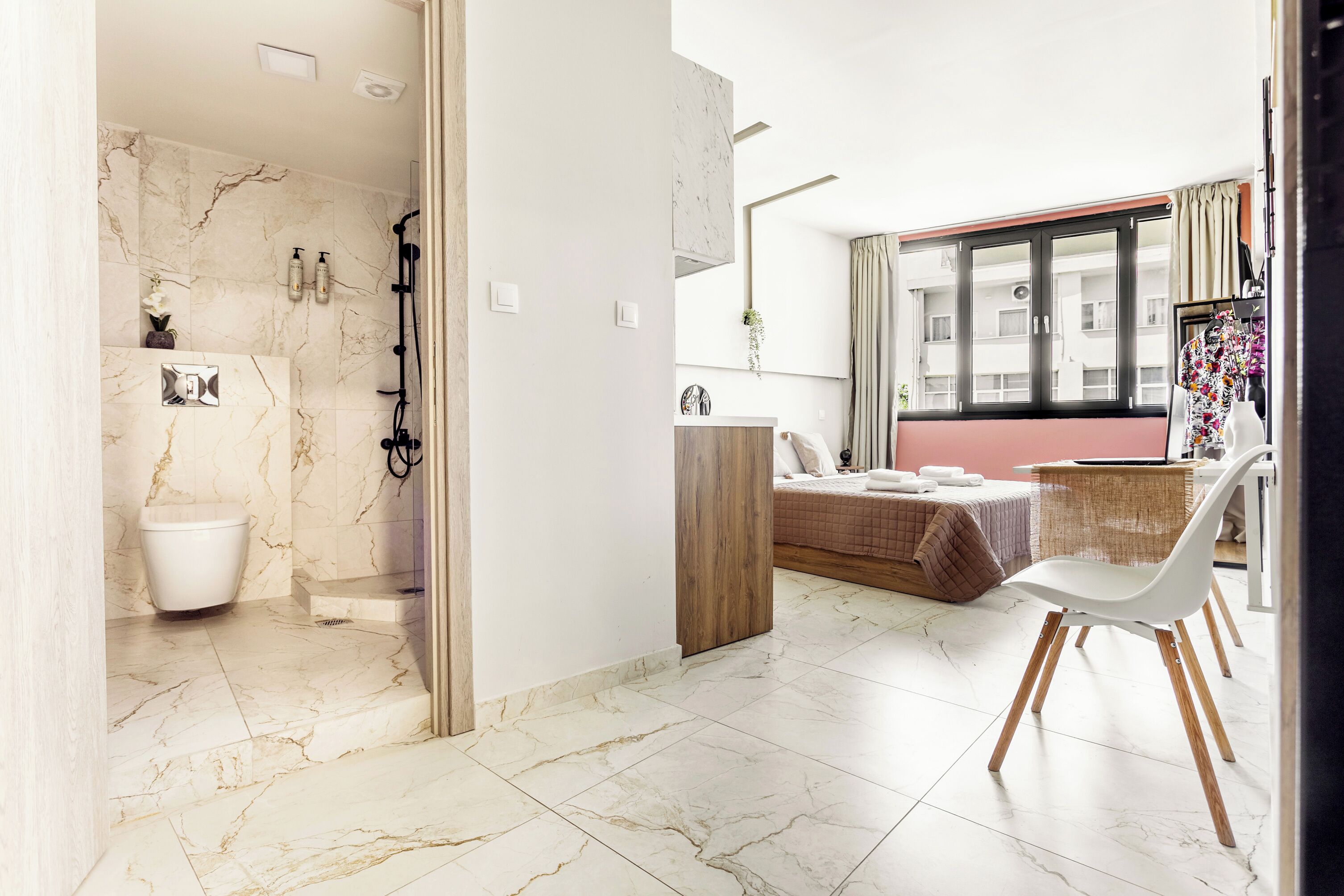 A modern bathroom with a marble floor, a toilet, a shower, and a vanity with a mirror.