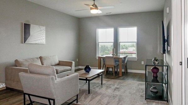 A living room with a sofa, coffee table, and a TV mounted on the wall.