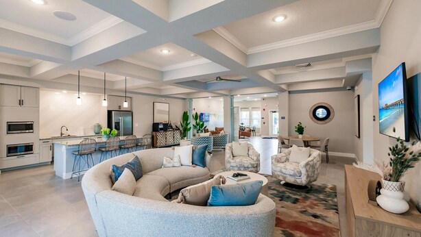 A spacious living area with a curved sofa, a dining area, and a kitchen with modern appliances. - Landing | Spectacular 1BD, Pool, Yoga Studio (Cape Coral)