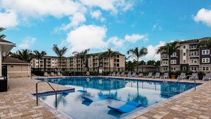 A rectangular swimming pool with blue lounge chairs and a tiled deck. - Landing | Spectacular 1BD, Pool, Yoga Studio (Cape Coral)