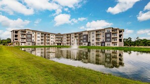 A multi-story residential building with a reflective water feature in front. - Landing | Spectacular 1BD, Pool, Yoga Studio (Cape Coral)