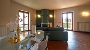 Amplia sala de estar con una mesa de comedor de vidrio, un sofá verde y una chimenea.