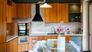 Una cocina moderna con armarios de madera, una isla central con asientos, horno empotrado e iluminación colgante.
