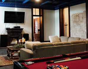 Una sala de estar acogedora con mesa de billar, chimenea y televisor.