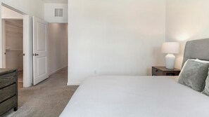 Un dormitorio con cama, mesita de noche, lámpara y armario.