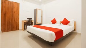 A bedroom with a bed, a desk, and a wardrobe. - Grande Inn (Erode)