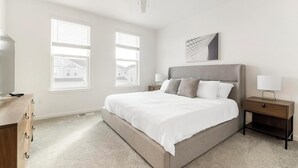 A bedroom with a large bed, two bedside tables, a dresser, and two windows with blinds. - Landing | Beautiful 3BD, Gym (Davenport)