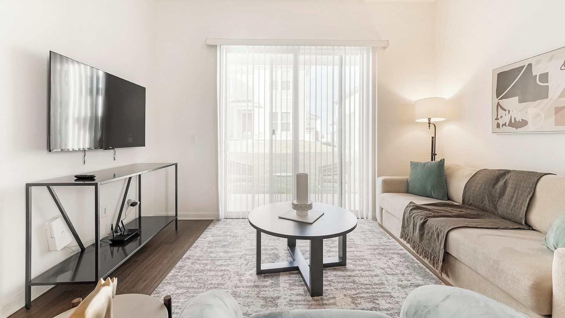 Ein modernes Wohnzimmer mit Flachbildfernseher, Glastisch, Sofa und Lampe.