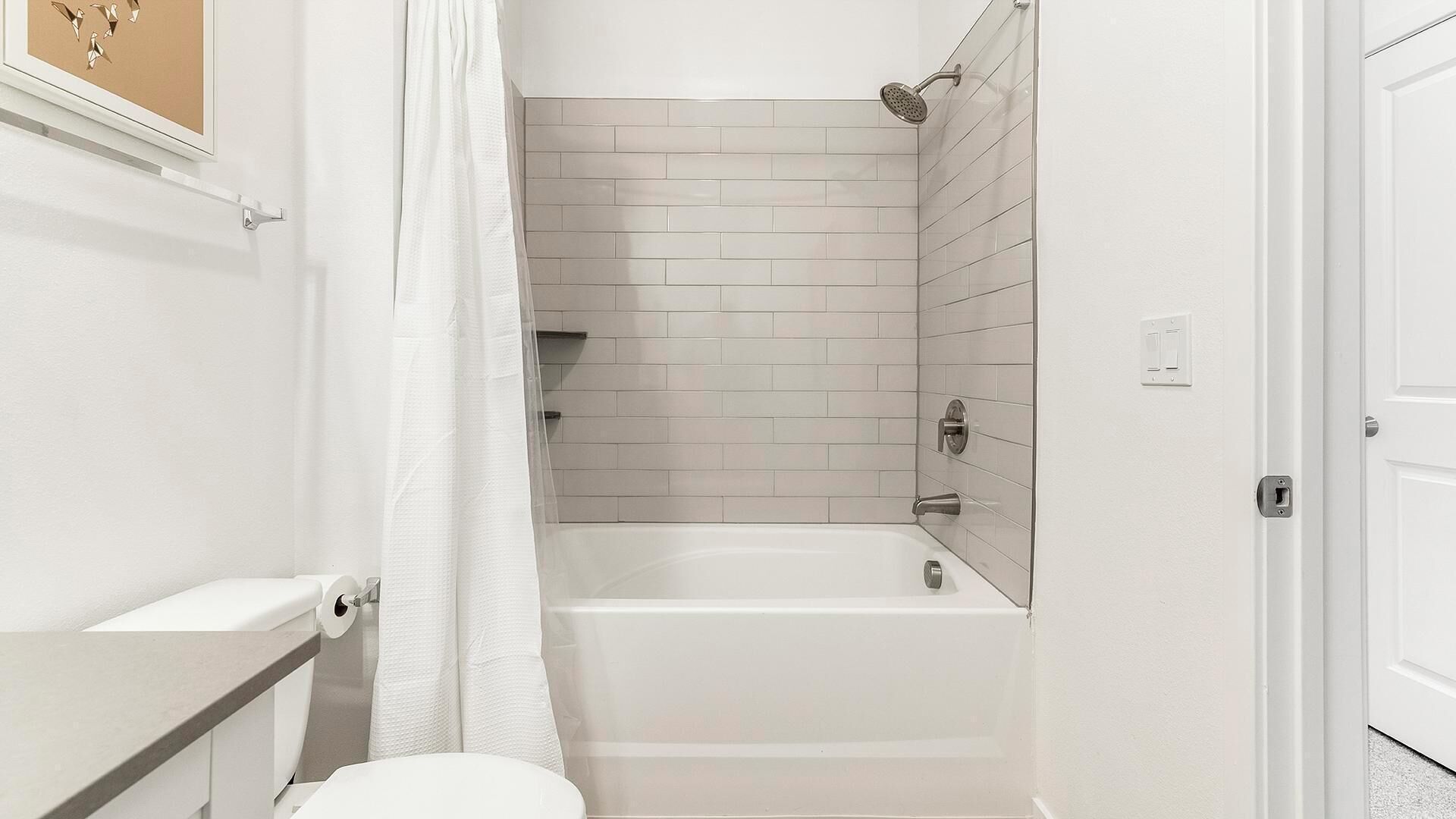 A bathroom with a white bathtub, a toilet, and a shower area with a glass door.