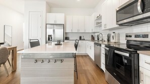 A modern kitchen with white cabinetry, a stainless steel refrigerator, a built-in oven, and a microwave. - Landing | Beautiful 3BD, Gym (Davenport)