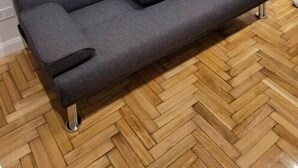 A grey sofa with armrests and a central console, placed on a wooden parquet floor. - Apartment in Almagro (Near Parque Centenario and Hospital Italiano) (CABA)
