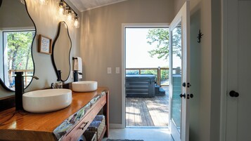 Casa de banho com um espelho grande, duas pias, um porta-toalhas e vista para um deck exterior.