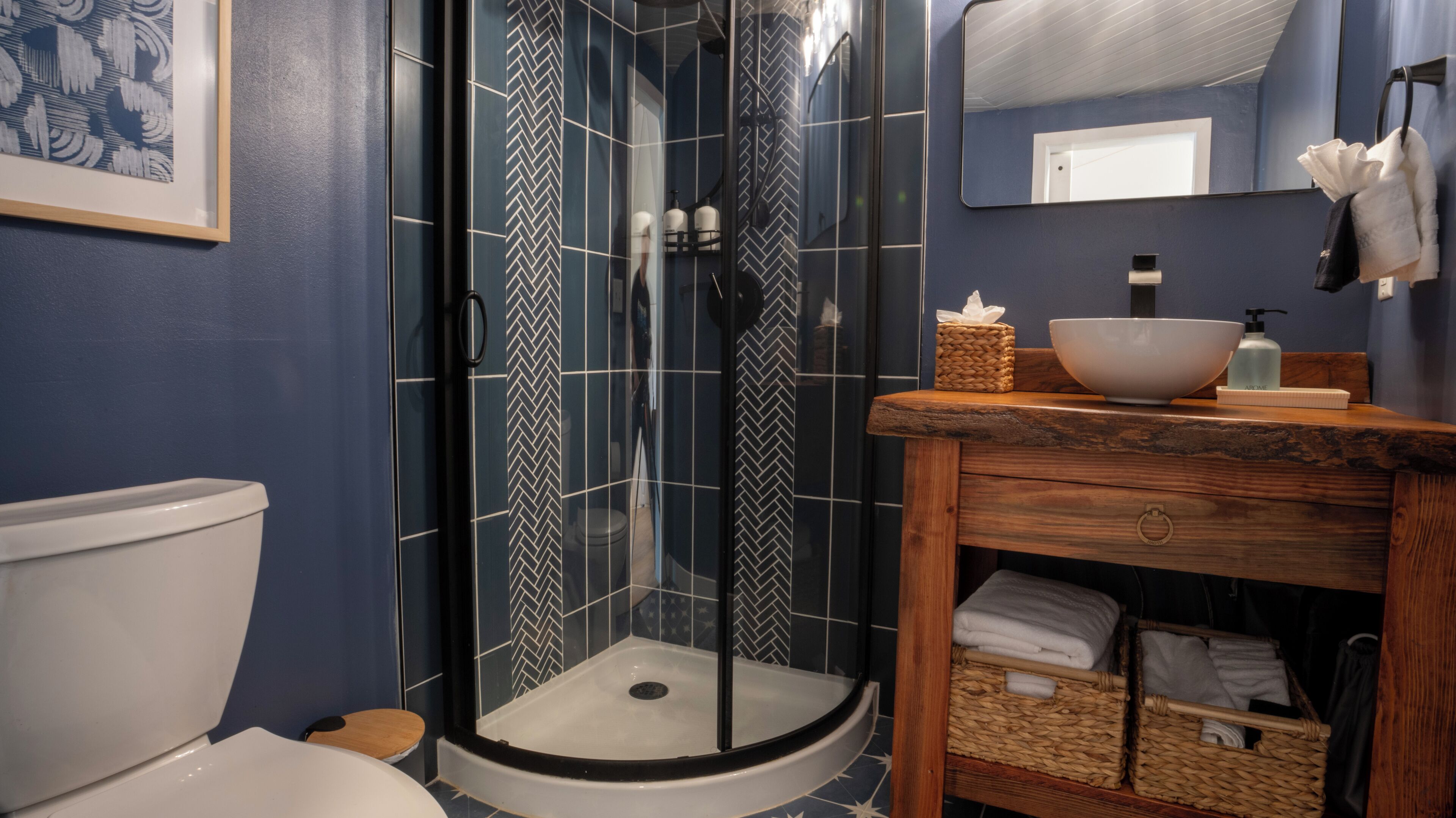 Un bagno con box doccia in vetro, un mobile bagno in legno, un lavandino bianco e un water.