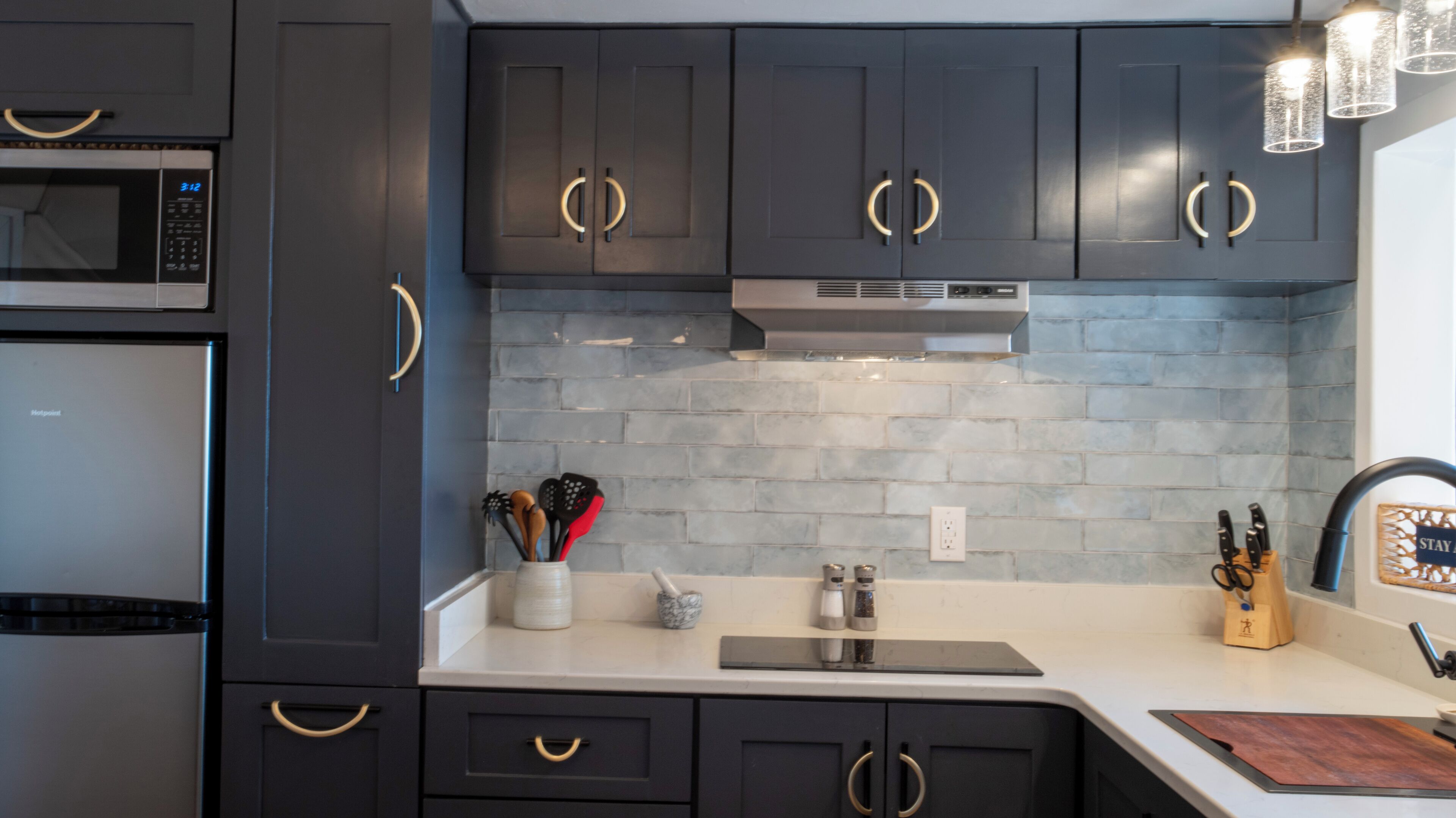 A modern kitchen with dark cabinetry, a microwave, and a stainless steel range hood.