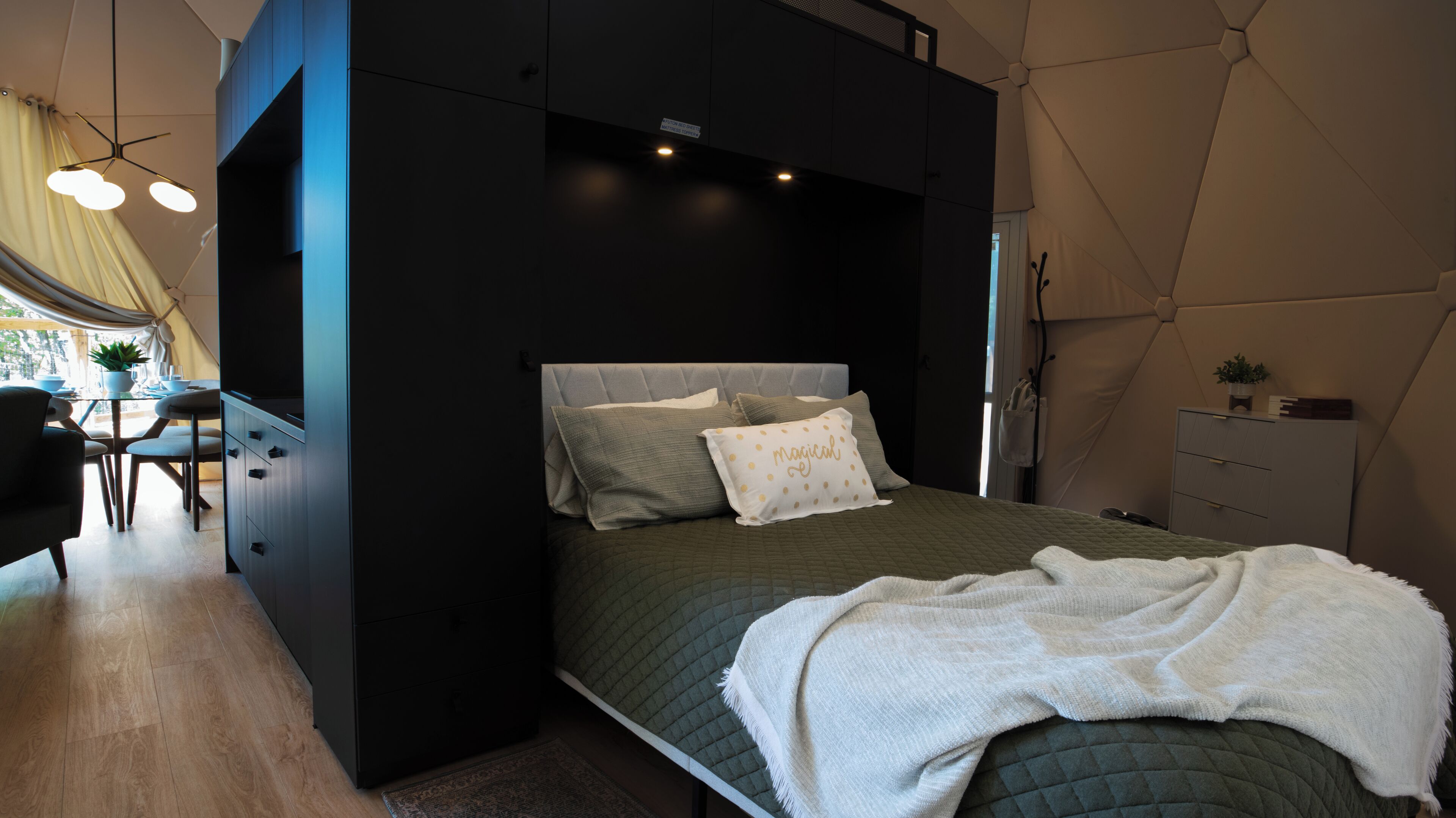 A modern bedroom with a bed, bedside tables, and a desk area.