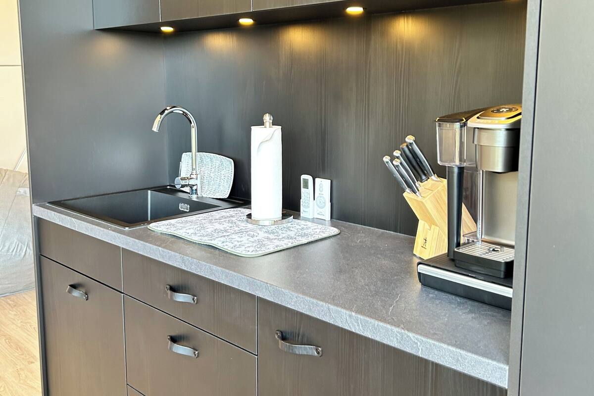 A modern kitchen with a built-in sink, stainless steel appliances, and wooden cabinets.