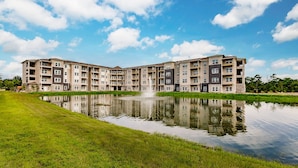 Een meerlaags woongebouw met een reflecterend waterpartij ervoor.