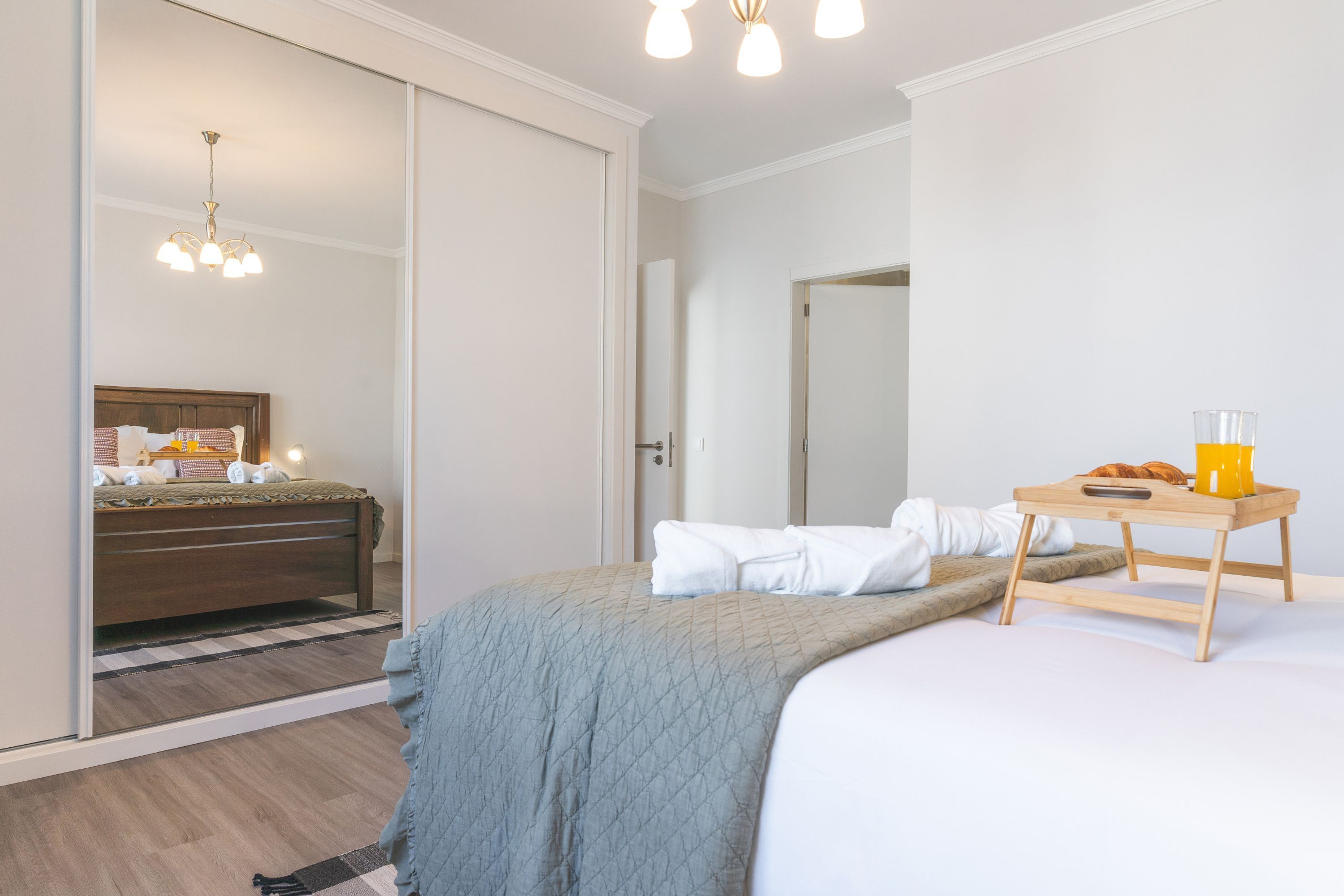 Een hotelkamer met een bed, een houten bureau, een spiegel en een kledingkast.