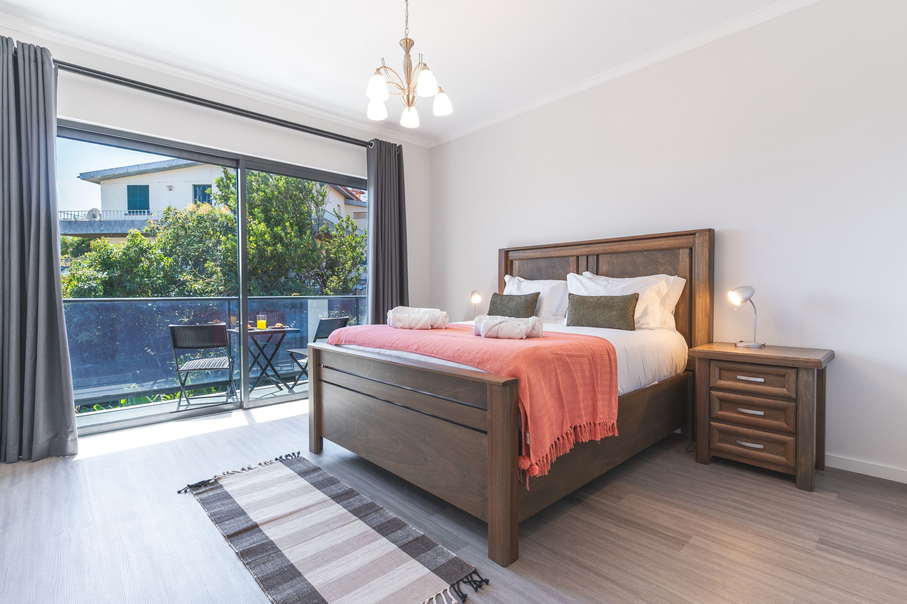 Une chambre avec un grand lit, une table de chevet, une chaise et une vue sur l’extérieur.