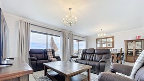 A modern living room with leather sofas, a wooden coffee table, and a chandelier. - Blue Outlook Retreat by Atlantic Holiday (Santa Cruz)