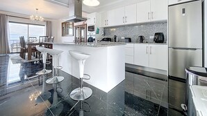 A modern kitchen with a central island, stainless steel appliances, and a view to the outside. - Blue Outlook View by Atlantic Holiday (Santa Cruz)