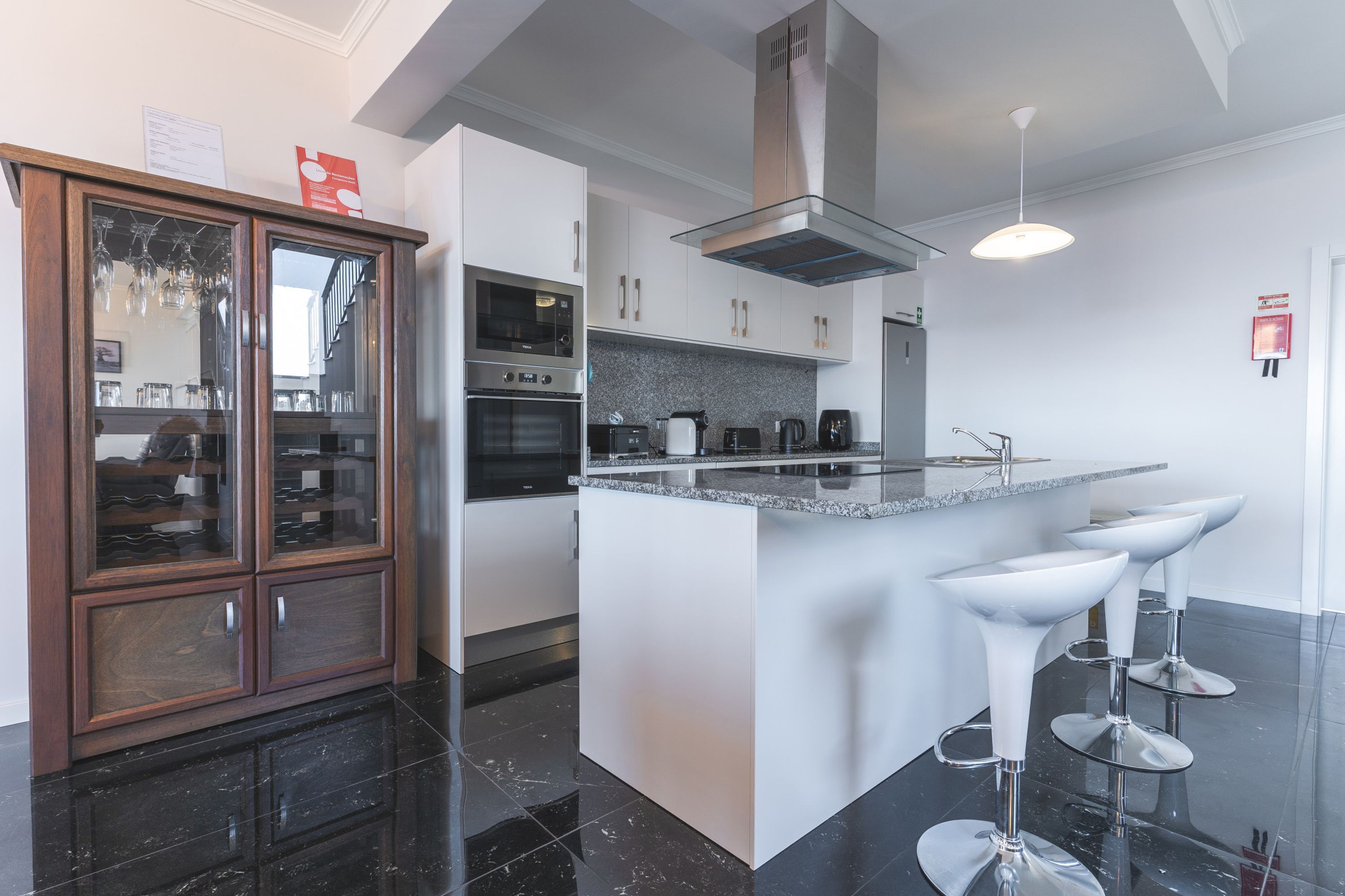 A modern kitchen with a central island, stainless steel appliances, and bar stools.