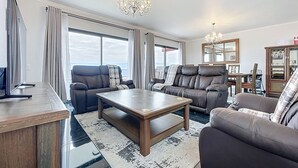 A modern living room with a sofa, a coffee table, and a chandelier. - Blue Outlook View by Atlantic Holiday (Santa Cruz)