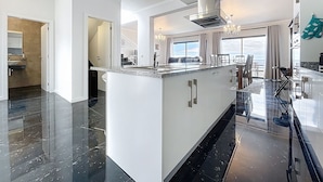 A modern kitchen with a central island, a dining area with a view, and a spacious living area. - Blue Outlook View by Atlantic Holiday (Santa Cruz)
