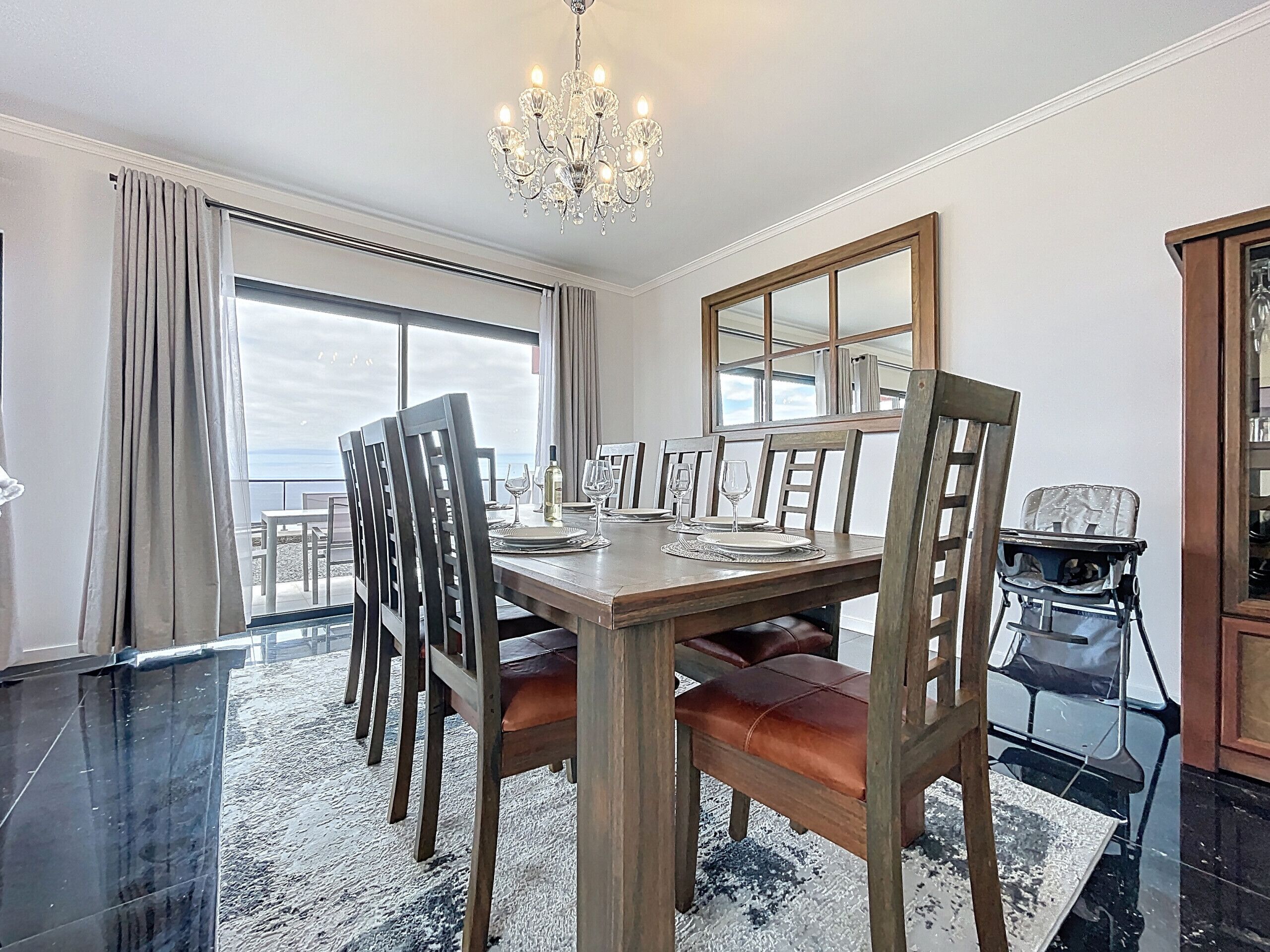 A dining area with a wooden table, chairs, and a chandelier.