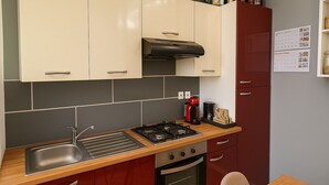 Una cocina compacta con estufa a gas, un lavamanos y una cafetera.