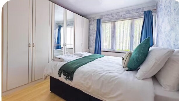 Une chambre à coucher avec un lit, une armoire et une fenêtre avec des rideaux.