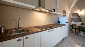 Una cocina moderna con un lavamanos de acero inoxidable, encimera de madera y armarios blancos.