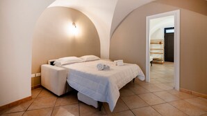 Un dormitorio con una cama, una mesita de noche, una lámpara de pared y un techo abovedado.