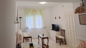 A compact living space with a dining area, a television, and a bed.