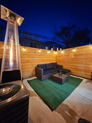 Un patio exterior con calefacción integrada, un sofá y una mesa de centro.
