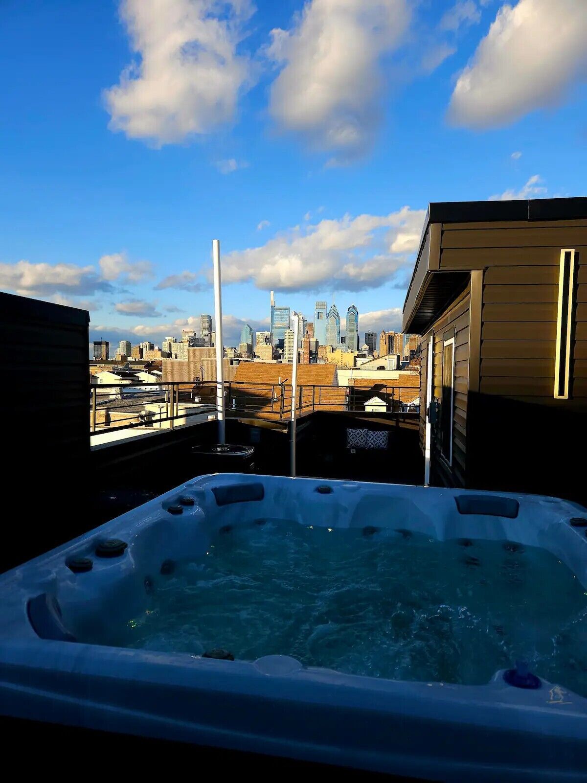 A hot tub on a rooftop with a city skyline in the background.