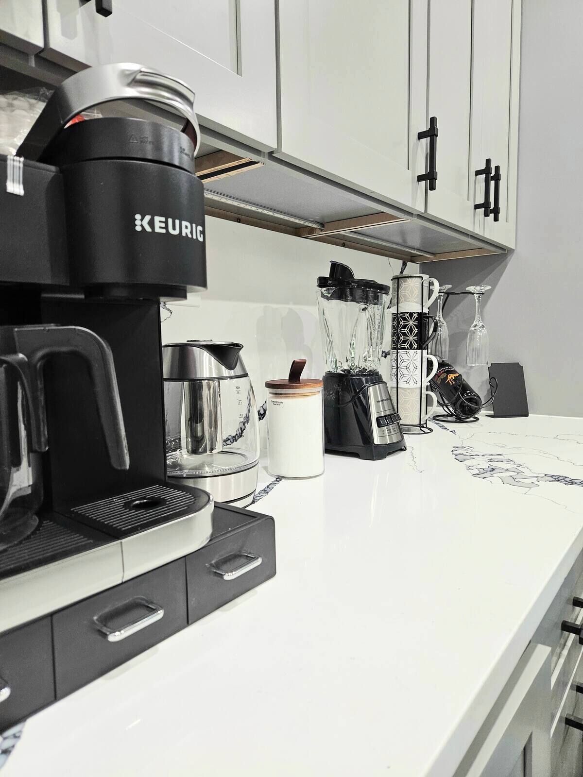 A modern kitchen with a Keurig coffee maker, a blender, and a coffee machine.