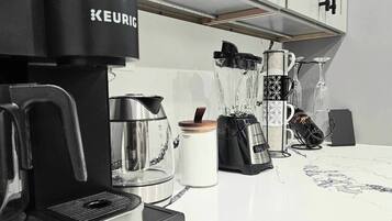 A modern kitchen with a Keurig coffee maker, a blender, and a coffee machine.