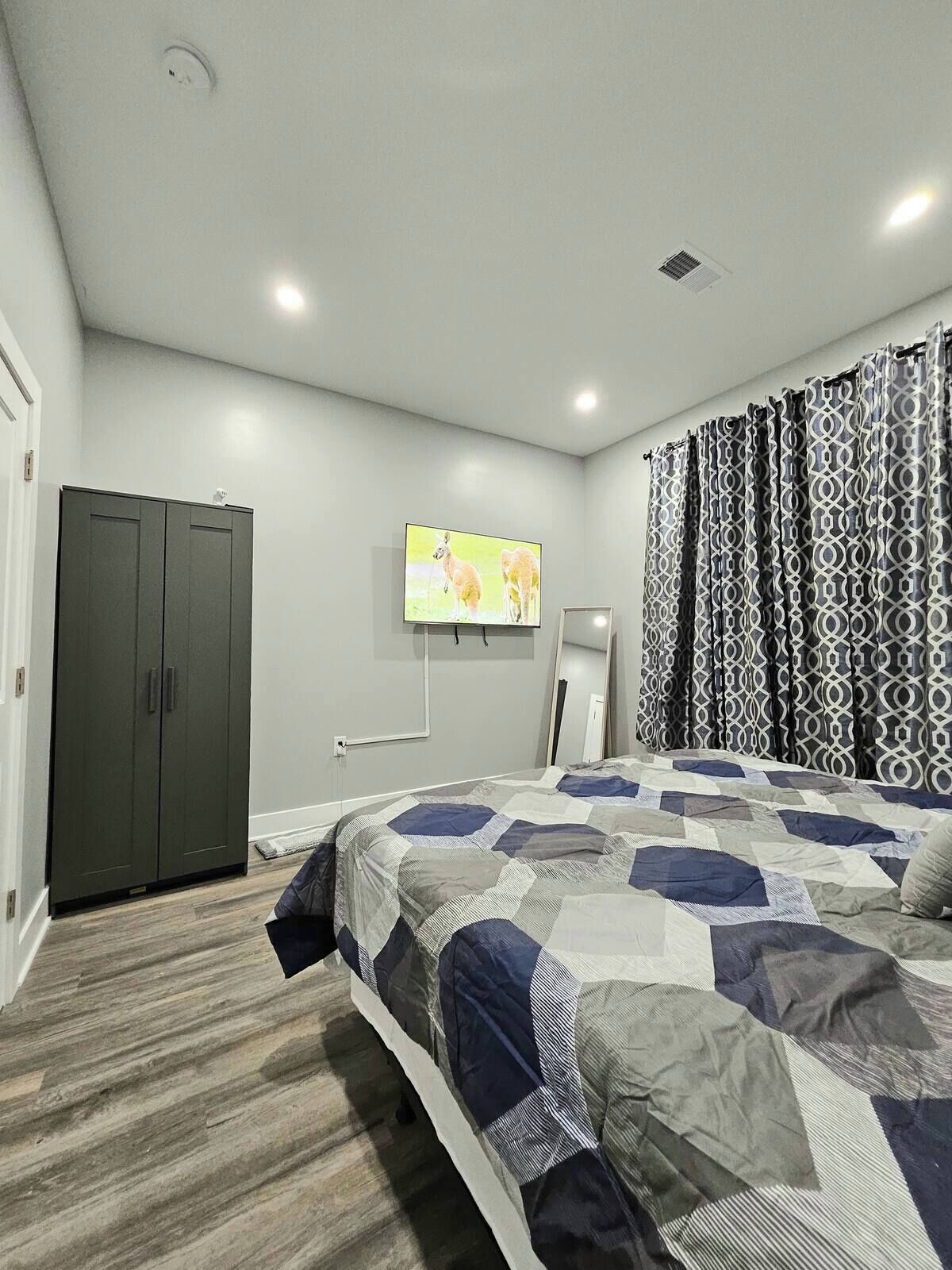 Une chambre à coucher avec un lit, une armoire, un téléviseur et des rideaux à motifs.