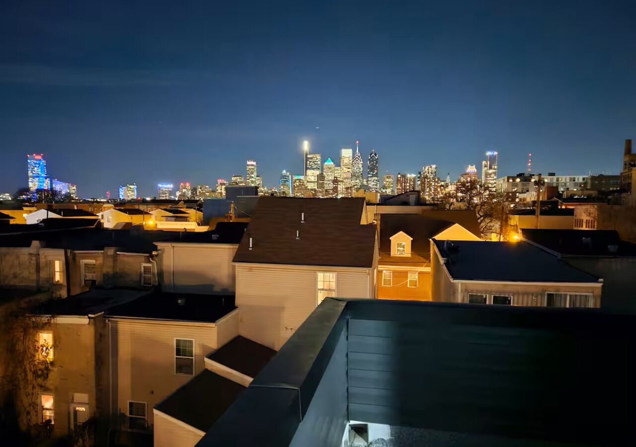A nighttime cityscape with a dense cluster of buildings, including residential houses and commercial skyscrapers.