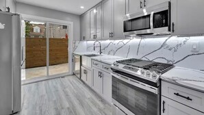 Una cocina moderna con armarios blancos, una estufa de acero inoxidable y un microondas.