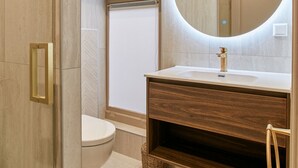 Een moderne badkamer met een grote spiegel, een houten wastafelmeubel en een toilet.